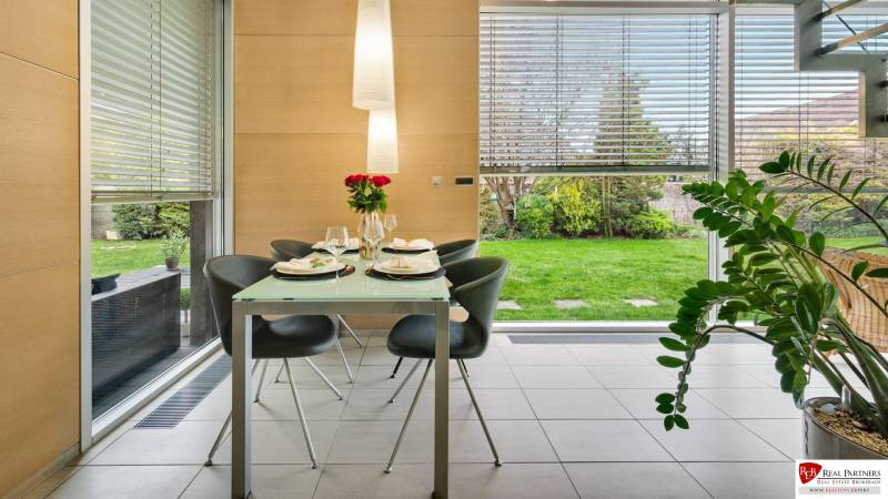 Predaj moderná 5 izbová vila, 265 m2, pozemok 953 m2, bazén,BA II. - Jedáleň na ulici Imelová a Vila, stôl s prestieraním, výhľad do záhrady.