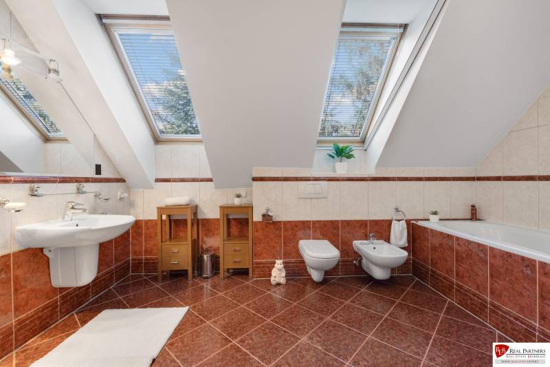 Predaj luxusná 5 izbová Vila,440 m2,pozemok 1061m2,garáž,bazén,BA II. - Podkrovná kúpeľňa na ulici Hrušovská a Vila s vaňou, umývadlom a strešnými oknami.