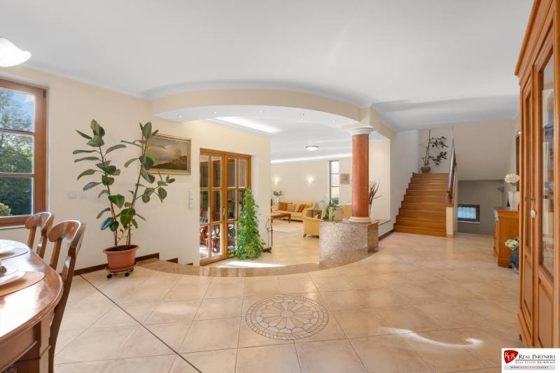 Predaj luxusná 5 izbová Vila,440 m2,pozemok 1061m2,garáž,bazén,BA II. - Interiér vily na ulici Hrušovská s priestranným obývacím priestorom a dreveným schodiskom.