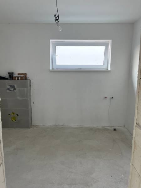 Novostavba- 4-izbový rodinný dom-Super Cena - Prázdna miestnosť v rodinnom dome s dreveným dekorom a úzkym oknom na stene.