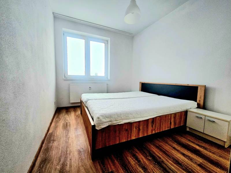 EXKLUZÍVNE- 2 Izbový byt v obci Motešice + parkovacie miesto  - Spálňa v 2-izbovom byte s podlahou s dreveným dekorom, posteľou a oknom.