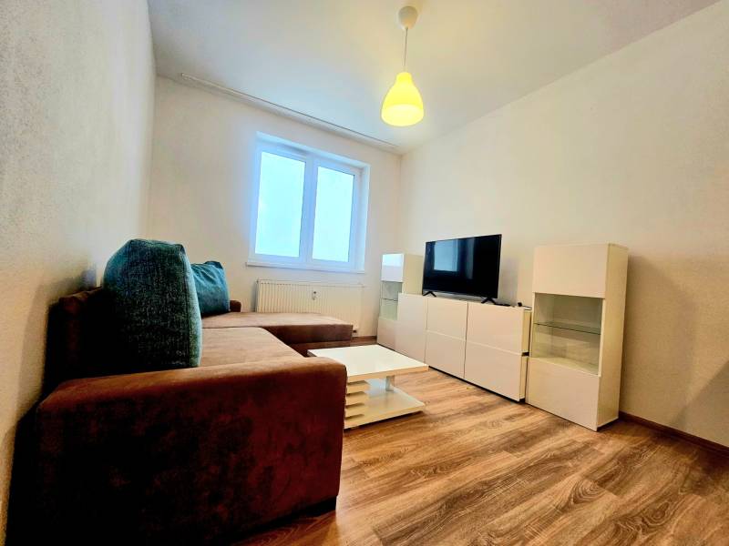 EXKLUZÍVNE- 2 Izbový byt v obci Motešice + parkovacie miesto  - Obývacia izba 2-izbového bytu s pohovkou, televízorom a podlahou s dreveným dekorom.