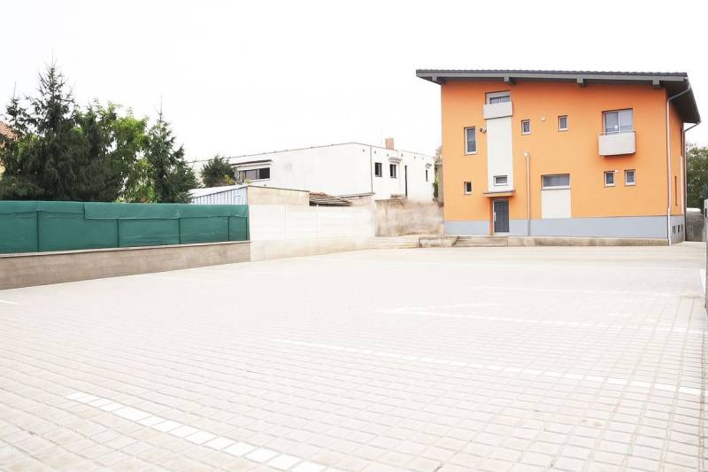 Prenájom ubytovacieho zariadenia – Šaľa Veča s kapacitou 50 osôb - Oranžová budova v Šali so strmou strechou a spevnenou parkovacou plochou.