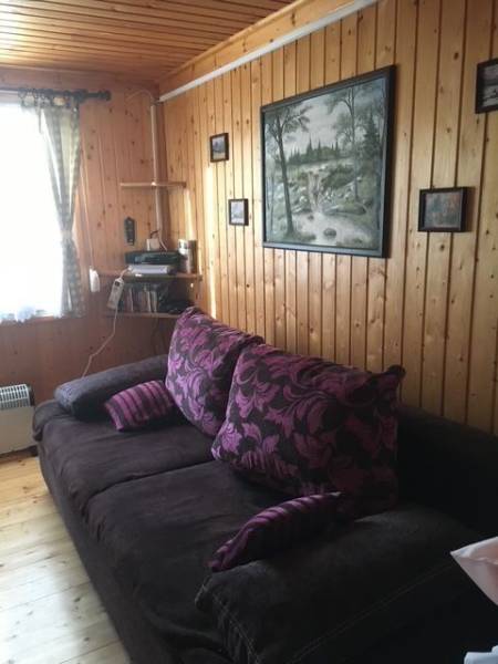 Záhrada na predaj – Kráľová nad Váhom 29 900 € - Dohoda Možná - Drevenými panelmi obložená stena s pohovkou, obrazom a poličkou v chate.