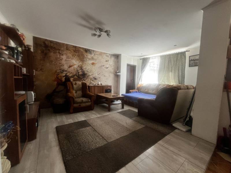 Rodinný dom s prístavbou na  podnikanie – Tešedíkovo - Obývacia izba v rodinnom dome s pohovkou, kreslami a nástennou maľbou za sedením.