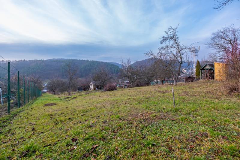 CHATKA SO ZÁHRADOU, PREŠOV – ŠIDLOVEC - Záhrada s výhľadom na kopce a chatu v Prešove, obklopená stromami a plotom.