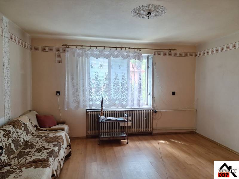 Výborný rodinný dom pre pohodlné bývanie - Obývacia izba v rodinnom dome s podlahou s dreveným dekorom a pohovkou.