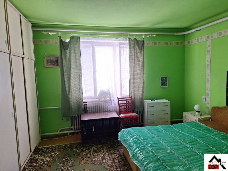 Výborný rodinný dom pre pohodlné bývanie - Zelená izba v rodinnom dome s posteľou, skriňou a koberec.