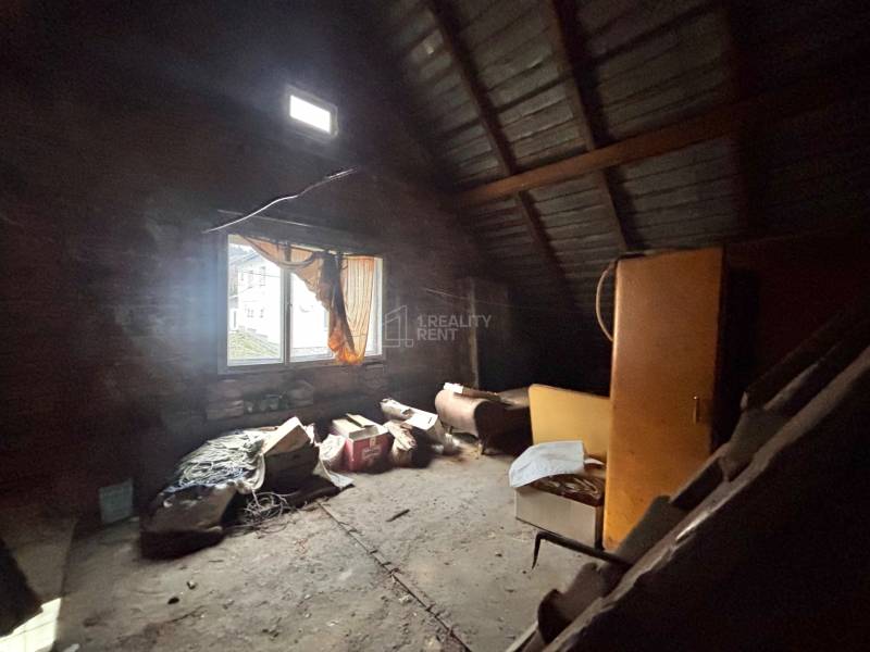 Predaj rodinného domu v Skalitom  - Podkrovná miestnosť s oknom v rodinnom dome plná starých predmetov a nábytku.