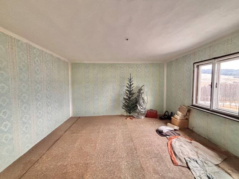 Predaj rodinného domu v Skalitom  - Izba v rodinnom dome s modrými tapetami, stromček, okno a uložené predmety.