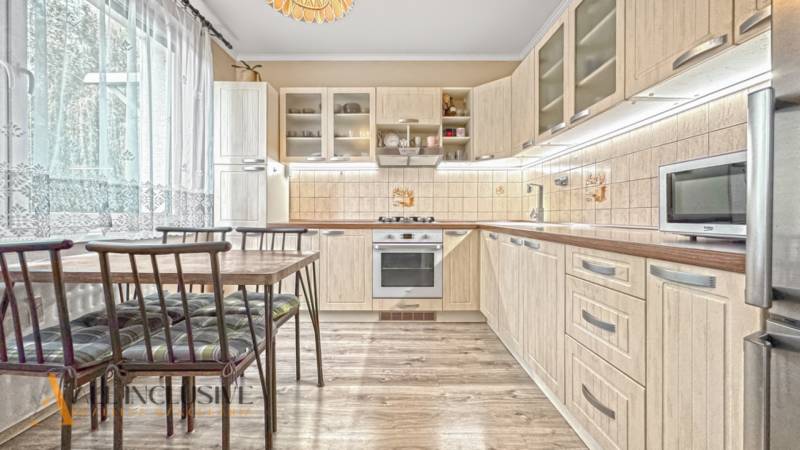 PRÍJEMNÝ 3 IZBOVÝ BYT | P.O.HVIEZDOSLAVA | TOPOĽČANY - Kuchyňa v 3-izbovom byte s podlahou s dreveným dekorom, svetlým nábytkom a jedálenským stolom.