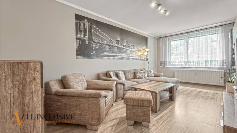 PRÍJEMNÝ 3 IZBOVÝ BYT | P.O.HVIEZDOSLAVA | TOPOĽČANY - Útulná obývačka so sedačkou, stolíkom a podlahou s dreveným dekorom v 3-izbovom byte.