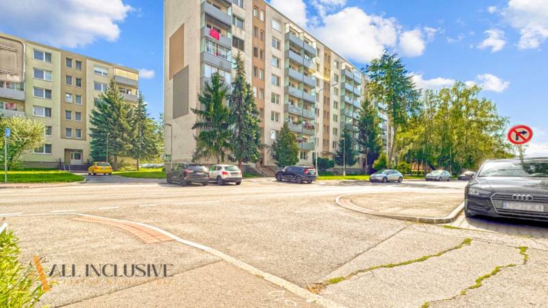 PRÍJEMNÝ 3 IZBOVÝ BYT | P.O.HVIEZDOSLAVA | TOPOĽČANY - Bytovky na ulici P.O. Hviezdoslava v Topoľčanoch, autá na parkovisku, zeleň okolo.
