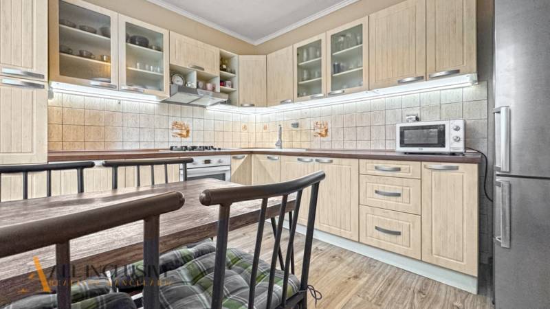 PRÍJEMNÝ 3 IZBOVÝ BYT | P.O.HVIEZDOSLAVA | TOPOĽČANY - Kuchyňa so svetlým nábytkom, jedálenským stolom a podlahou s dreveným dekorom v 3-izbovom byte.