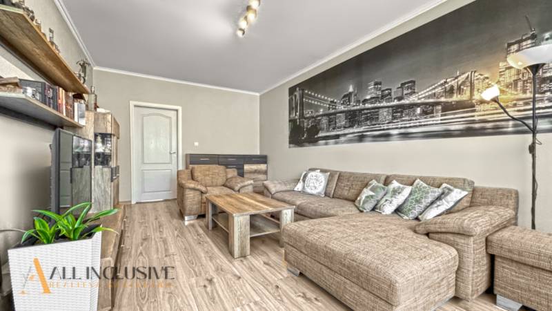 PRÍJEMNÝ 3 IZBOVÝ BYT | P.O.HVIEZDOSLAVA | TOPOĽČANY - Obývačka s rohovo umiestnenou sedačkou a podlahou s dreveným dekorom v 3-izbovom byte.