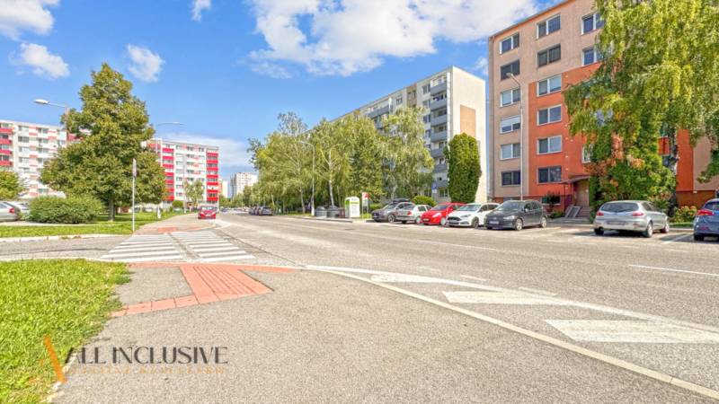 PRÍJEMNÝ 3 IZBOVÝ BYT | P.O.HVIEZDOSLAVA | TOPOĽČANY - Ulica P.O. Hviezdoslava v Topoľčanoch s bytovkami a zaparkovanými autami pri 3-izbovom byte.