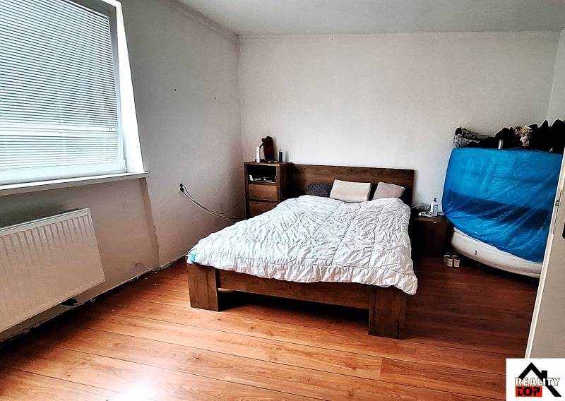 Investujte do budúcnosti - Spálňa v rodinnom dome s posteľou, komodou a podlahou s dreveným dekorom.