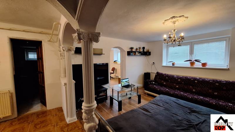 Investujte do budúcnosti - Obývačka v rodinnom dome s pohovkou, sklom stolom a stĺpmi.