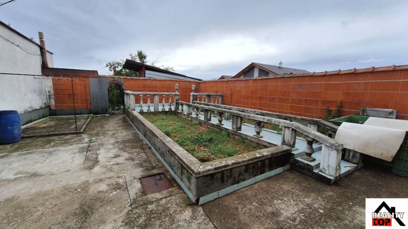 Investujte do budúcnosti - Dvor rodinného domu v Zacharovciach s kvetinovým záhonom a betónovým chodníkom.