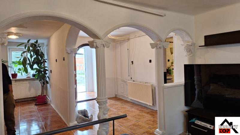 Investujte do budúcnosti - Interiér rodinného domu s oblúkovými stĺpmi a podlahou s dreveným dekorom.