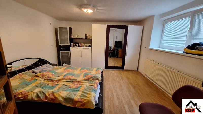 Investujte do budúcnosti - Spálňa s posteľou, skriňou a podlahou s dreveným dekorom v rodinnom dome.