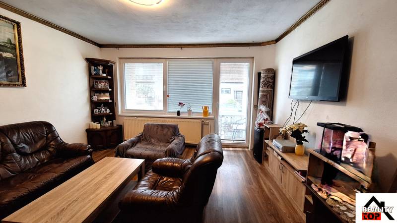 Investujte do budúcnosti - Obývacia izba v rodinnom dome s koženým nábytkom a podlahou s dreveným dekorom.