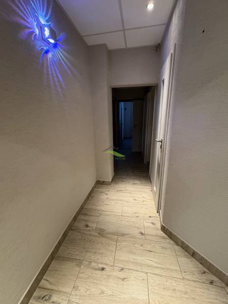 NOVINKA .... Na  predaj 3 izbový byt na sídlisku SNP v Michalovciach - Chodba s podlahou s dreveným dekorom, osvetlením a bielymi stenami v 3-izbovom byte.