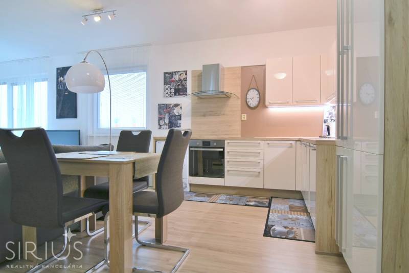 ANTOLSKÁ, 2-i byt, 54 m2 – novostavba REZIDENCIA DRAŽDIAK, zariadený - Moderná kuchyňa s jedálenským stolom, bielymi skrinkami a podlahou s dreveným dekorom v 2-izbovom byte.