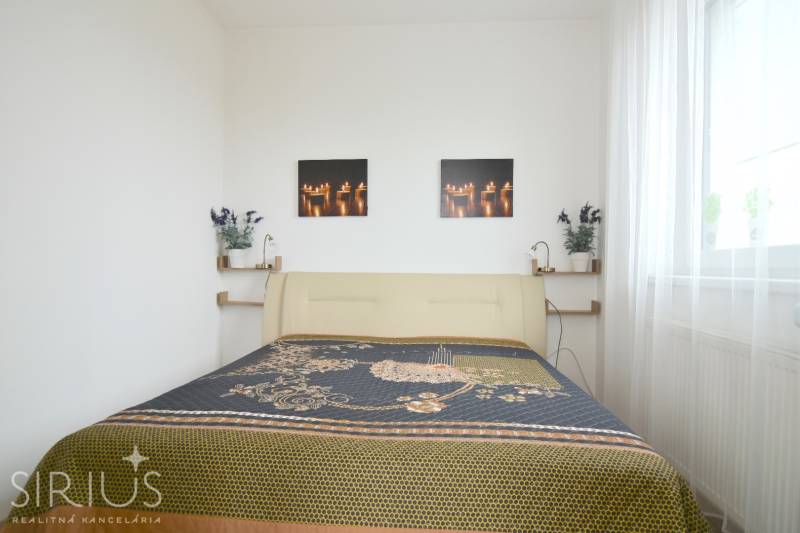 ANTOLSKÁ, 2-i byt, 54 m2 – novostavba REZIDENCIA DRAŽDIAK, zariadený - Spálňa v 2-izbovom byte so svetlou posteľou a dekoračnými obrázkami na stene.