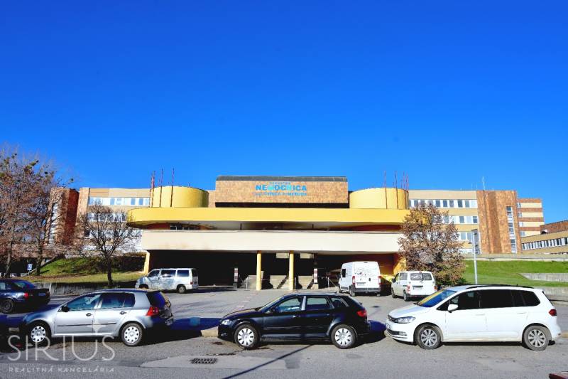 ANTOLSKÁ, 2-i byt, 54 m2 – novostavba REZIDENCIA DRAŽDIAK, zariadený - Budova nemocnice na Antolskej ulici v Petržalke, Bratislava, s parkoviskom a autami.