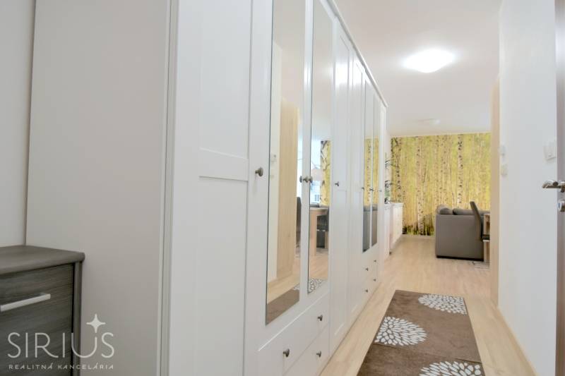 ANTOLSKÁ, 2-i byt, 54 m2 – novostavba REZIDENCIA DRAŽDIAK, zariadený - Chodba s bielou zrkadlovou skriňou a podlahou s dreveným dekorom v 2-izbovom byte.