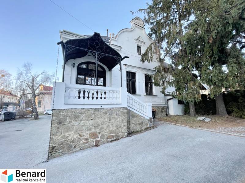 PREŠOV-ŠIRŠIE CENTRUM,POLYFUNKČNÁ BUDOVA,VL.PARKOVISKO,UL.VAJANSKÉHO - Budova na Vajanského ulici v Prešove s kamennou terasou a stromami.