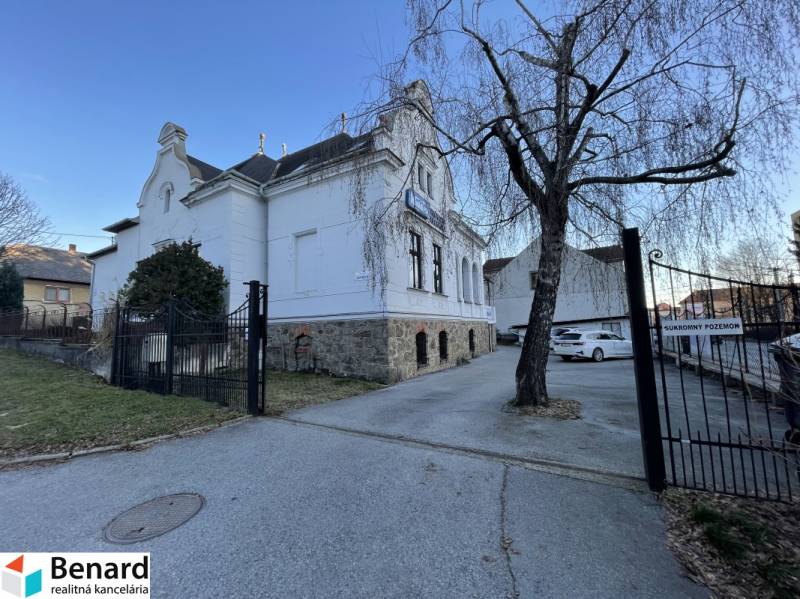 PREŠOV-ŠIRŠIE CENTRUM,POLYFUNKČNÁ BUDOVA,VL.PARKOVISKO,UL.VAJANSKÉHO - Budova na Vajanského ulici v Prešove so stromom a zaparkovanými autami.