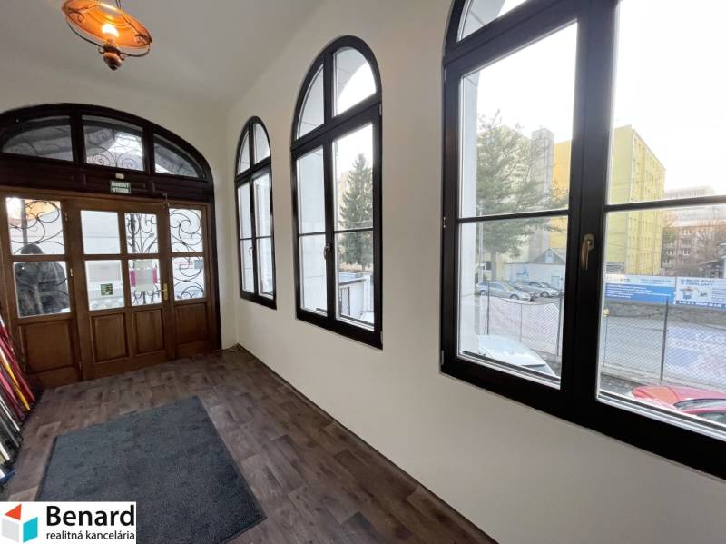 PREŠOV-ŠIRŠIE CENTRUM,POLYFUNKČNÁ BUDOVA,VL.PARKOVISKO,UL.VAJANSKÉHO - Budova s podlahou s dreveným dekorom a veľkými oknami na Vajanského ulici v Prešove.