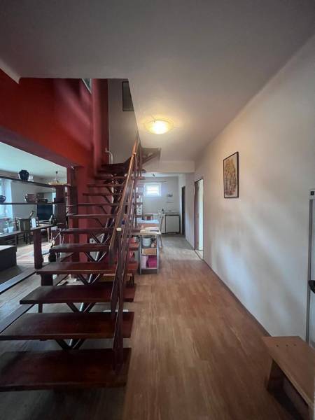 PRIESTRANNÝ 7-IZBOVÝ RODINNÝ DOM S VEĽKÝM POZEMKOM V DLHEJ NAD VÁHOM  - Interiér rodinného domu s drevenými schodmi a podlahou s dreveným dekorom.