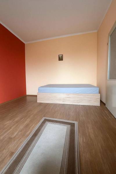 PRIESTRANNÝ 7-IZBOVÝ RODINNÝ DOM S VEĽKÝM POZEMKOM V DLHEJ NAD VÁHOM  - Izba v rodinnom dome s podlahou s dreveným dekorom, posteľou a červenou stenou.