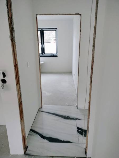 Novostavba 4-izbového rodinného dvojdomu v obci Žihárec - Rekonštrukcia interiéru rodinného domu s bielymi stenami a mramorovou dlažbou.