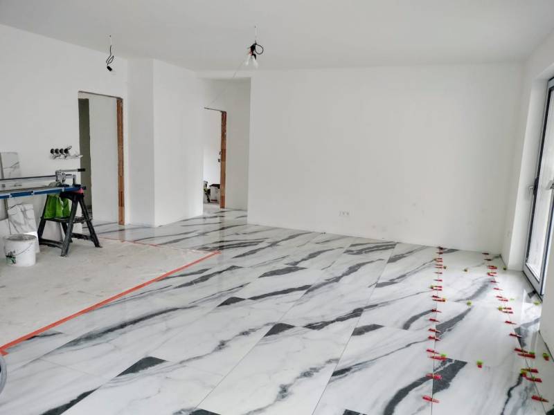 Novostavba 4-izbového rodinného dvojdomu v obci Žihárec - Interiér rodinného domu s podlahou s mramorovým dekorom a bielymi stenami.