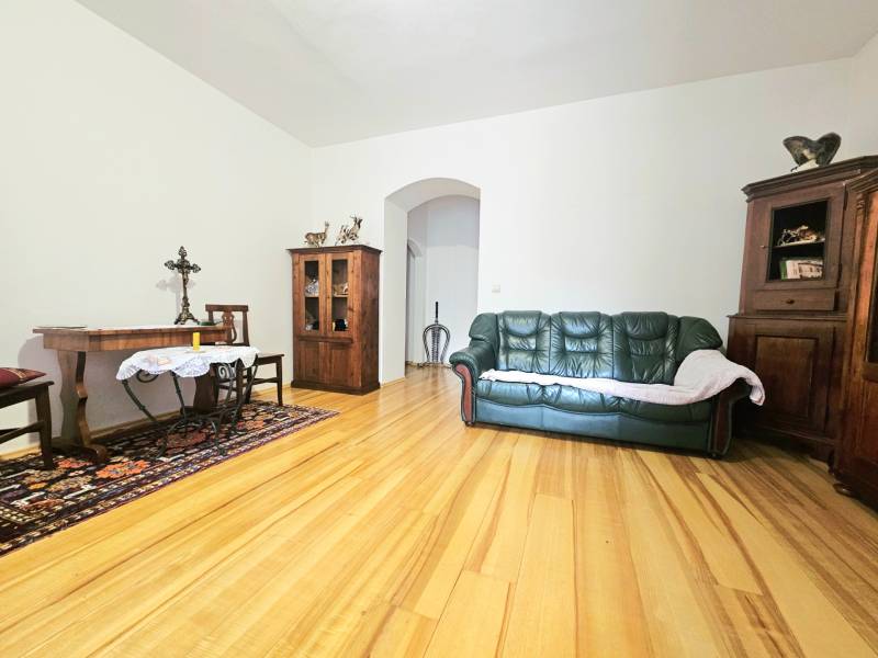  Veľkometrážny 3 izbový byt v kúpeľnom meste Trenčianske Teplice  - Obývacia izba v 3-izbovom byte s podlahou s dreveným dekorom, pohovkou a dreveným nábytkom.