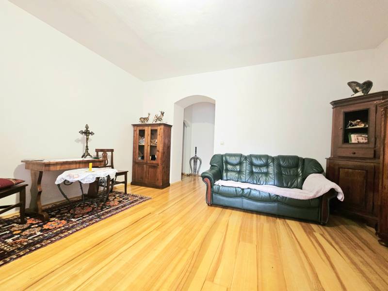  Veľkometrážny 3 izbový byt v kúpeľnom meste Trenčianske Teplice  - Obývacia izba v 3-izbovom byte s podlahou s dreveným dekorom a dreveným nábytkom.