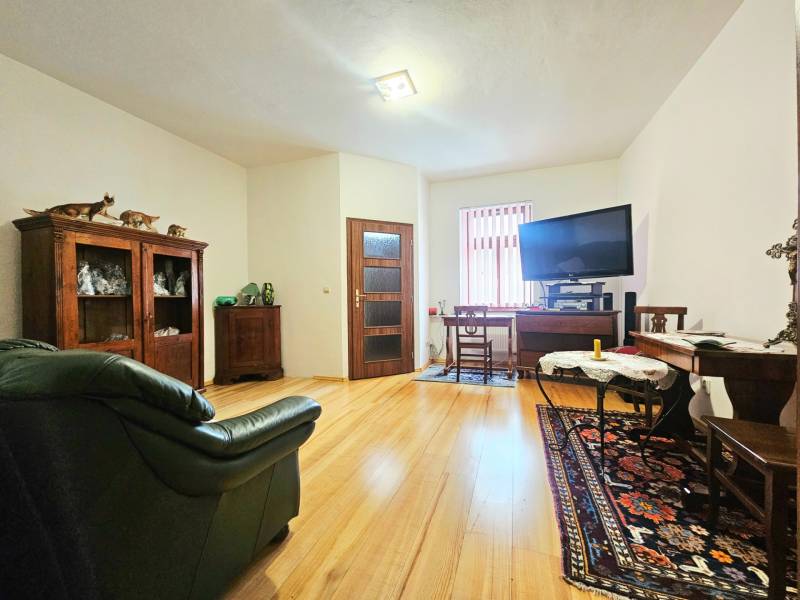  Veľkometrážny 3 izbový byt v kúpeľnom meste Trenčianske Teplice  - Obývačka v 3-izbovom byte s podlahou s dreveným dekorom, vybavená sedačkou a televízorom.