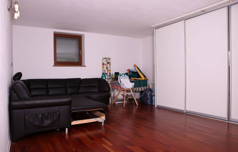 Na predaj rodinný dom na Súľovskej 56 v Bratislave - Rodinný dom s čiernou sedačkou, bielymi skriňami a podlahou s dreveným dekorom.