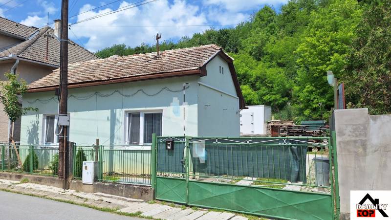 Rodinný dom po čiastočnej rekonštrukcii - Rodinný dom v Hajnáčke s jednopodlažným dizajnom, krytý strechou a zeleným plotom.