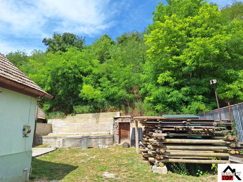 Rodinný dom po čiastočnej rekonštrukcii - Rodinný dom v Hajnáčke s drevom a zeleňou na dvore, obklopený bujnou prírodou.