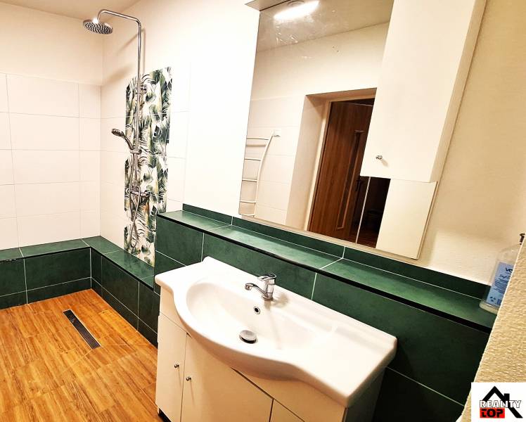 Rodinný dom po čiastočnej rekonštrukcii - Kúpeľňa v rodinnom dome s podlahou s dreveným dekorom a sprchou.