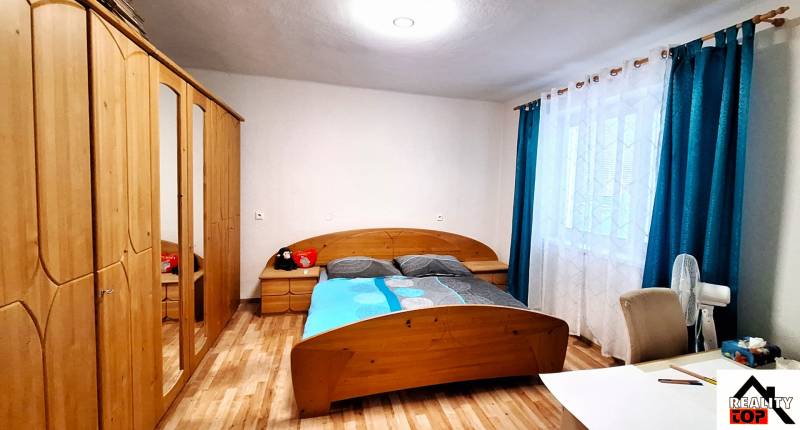 Rodinný dom po čiastočnej rekonštrukcii - Spálňa v rodinnom dome s posteľou, skriňou a podlahou s dreveným dekorom.