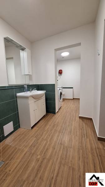 Rodinný dom po čiastočnej rekonštrukcii - Kúpeľňa v rodinnom dome s podlahou s dreveným dekorom a práčkou.