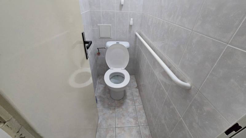 3-izbový byt so záhradou a garážou – Sadová ulica, Piešťany - Kúpeľňa s toaletou v 3-izbovom byte, obložená svetlými obkladmi, s úchytkou na stene.