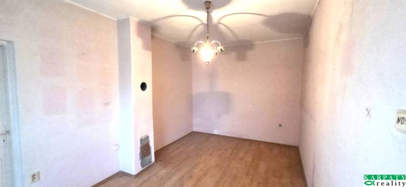 Na predaj rodinný dom Levice!. - Izba v rodinnom dome s podlahou s dreveným dekorom a závesným svietidlom.