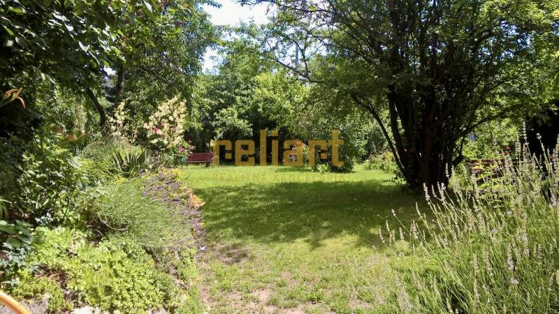 Horský Park:Na prenájom veľkometrážny, 4i, charizmatický byt - Záhrada s lavičkou, obklopená bujnou vegetáciou a stromami, vytvára pokojné prostredie.